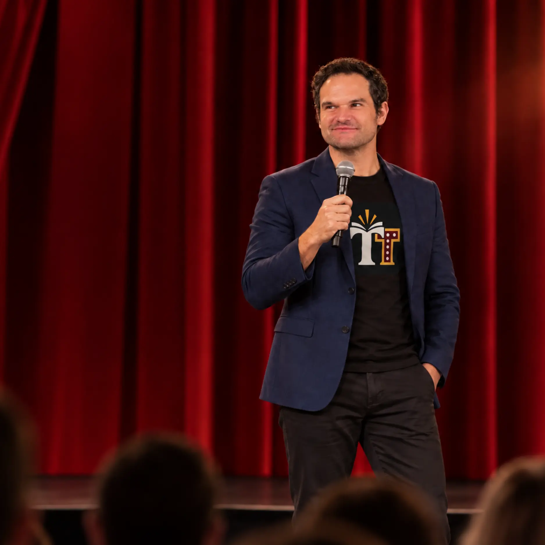 Mr. Jake performing on stage with a microphone in front of red curtains